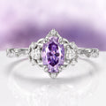 Esme Lavender Moissanite Ring Engagement Ring in 14K White Gold by Aquamarise Gold showcasing a vibrant oval lavender moissanite center stone flanked by sparkling colorless moissanite accents and an intricate nature-inspired band design from the Solid Gold Moissanite Engagement Rings collection.