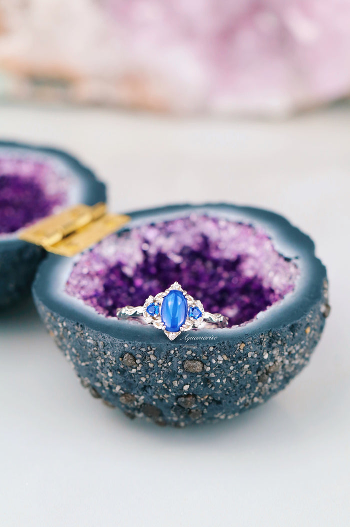 Esme Natural Star Sapphire Engagement Ring in Sterling Silver by Aquamarise, displayed inside an open purple geode, featuring an oval star sapphire with silver and gemstone accents.