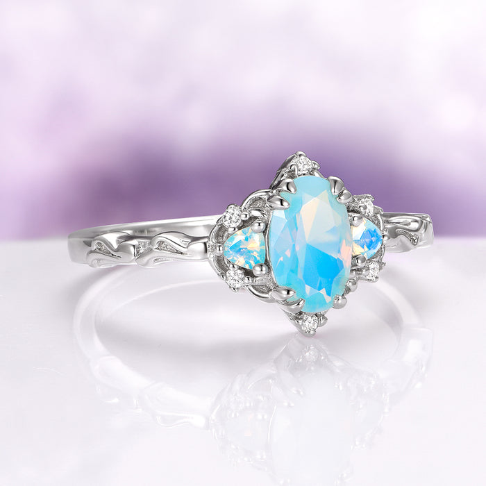 Esme Opalescent Blue Sapphire Mermaid Ring in 925 Sterling Silver featuring an oval opalescent blue sapphire with delicate side stones on an intricately carved silver band by Aquamarise.
