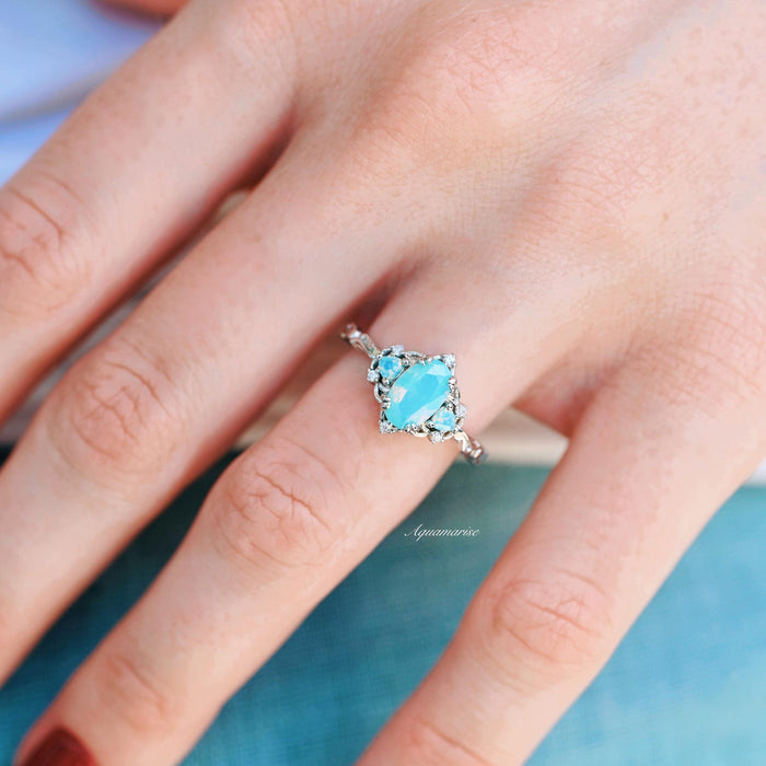 Esme Opalescent Blue Sapphire Mermaid Ring in 925 Sterling Silver with a marquise light blue sapphire centerpiece and delicate surrounding stones, styled on a hand against a soft background.