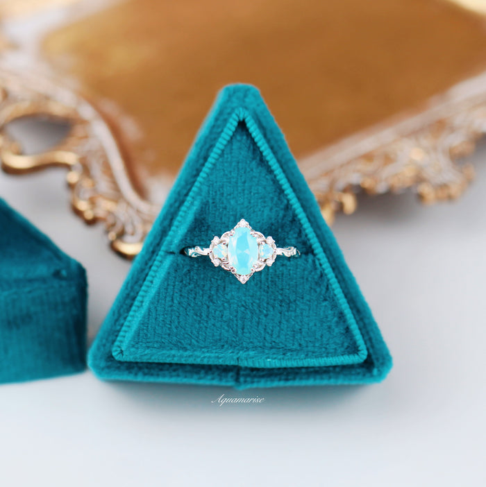 Esme Opalescent Blue Sapphire Mermaid Ring in 925 Sterling Silver with an opalescent light blue sapphire and delicate diamond accents, presented in a teal velvet triangular box by Aquamarise.