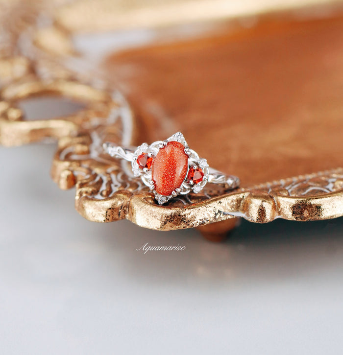 Esme Red Goldstone & Orange Sapphire Ring in Sterling Silver by Aquamarise featuring an oval red goldstone center flanked by vibrant orange sapphires with intricate silver detailing.