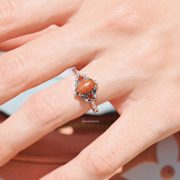 Esme Red Goldstone & Orange Sapphire Ring in Sterling Silver by Aquamarise featuring an oval red goldstone center with vibrant orange sapphires and delicate vintage-inspired silverwork on finger.