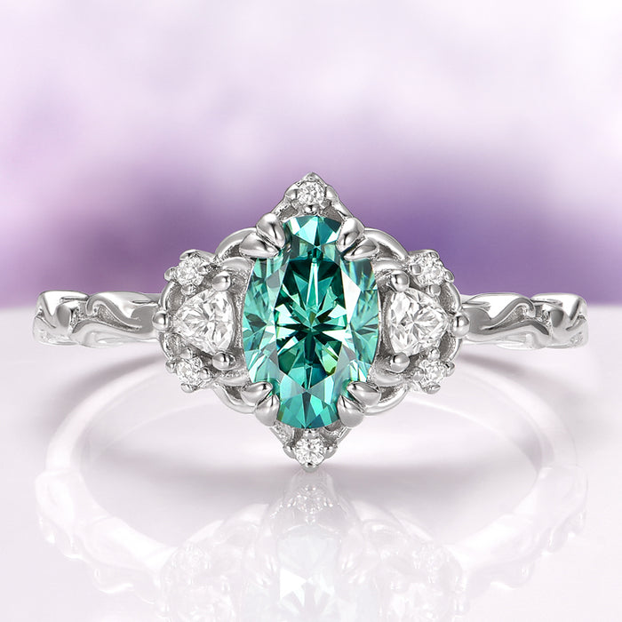 Esme Oval Cut Teal Moissanite Engagement Ring in 14K White Gold by Aquamarise Gold, featuring a vibrant teal center stone with sparkling accents in a nature-inspired design.
