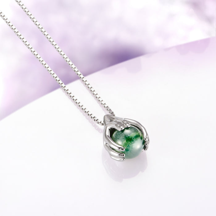 Ethereal Hold Moss Agate Pendant Necklace in Sterling Silver by Aquamarise, featuring sculpted sterling silver hands gently cradling a vivid natural moss agate gemstone on a delicate sterling silver chain, part of Necklaces, Moss Agate Jewelry, Birthstone Jewelry, and Meaningful Jewelry Gifts collections.