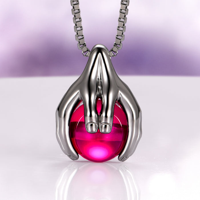 Ethereal Hold Ruby Pendant Necklace in Black Ruthenium by Aquamarise, featuring a sculpted black ruthenium sterling silver pendant shaped like hands cradling a vibrant round ruby, part of July Birthstone Jewelry, Lovers of the Dark™, and Meaningful Jewelry Gifts collections.