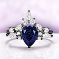 Evelyn Starry Night Ring Set in Black Ruthenium by Aquamarise featuring a pear-cut blue sandstone with marquise and round white stones in 925 sterling silver with black ruthenium finish.