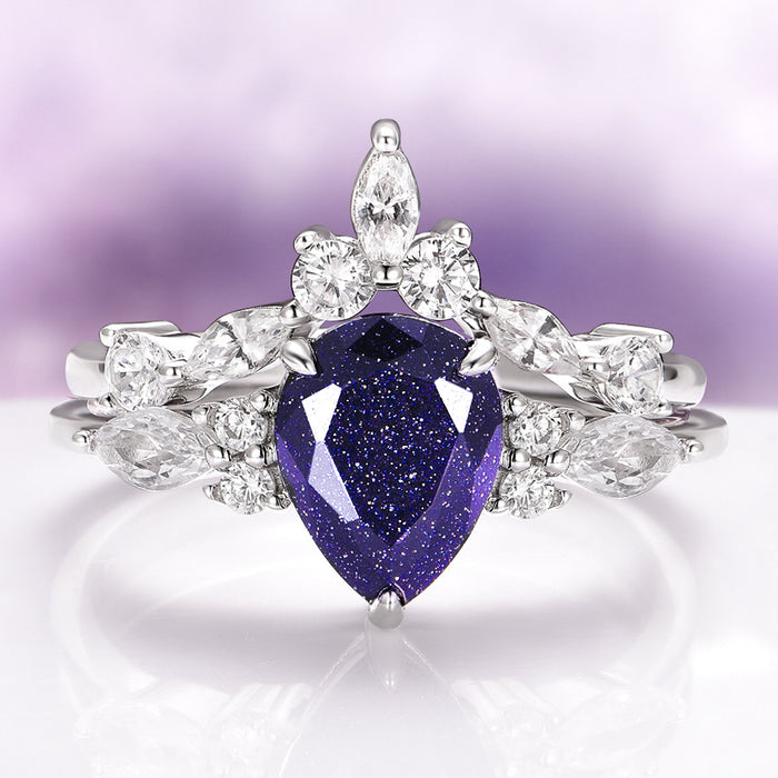 Evelyn Starry Night Engagement Ring Set in 14K White Gold by Aquamarise Gold, featuring a pear-shaped deep blue gemstone and sparkling white diamond accents in a celestial-inspired design.
