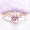 Everly Three Stone Oval Morganite Ring in 14K Rose Gold Vermeil by Aquamarise, featuring a 2 carat oval morganite center flanked by two simulated diamond accents in a classic setting.