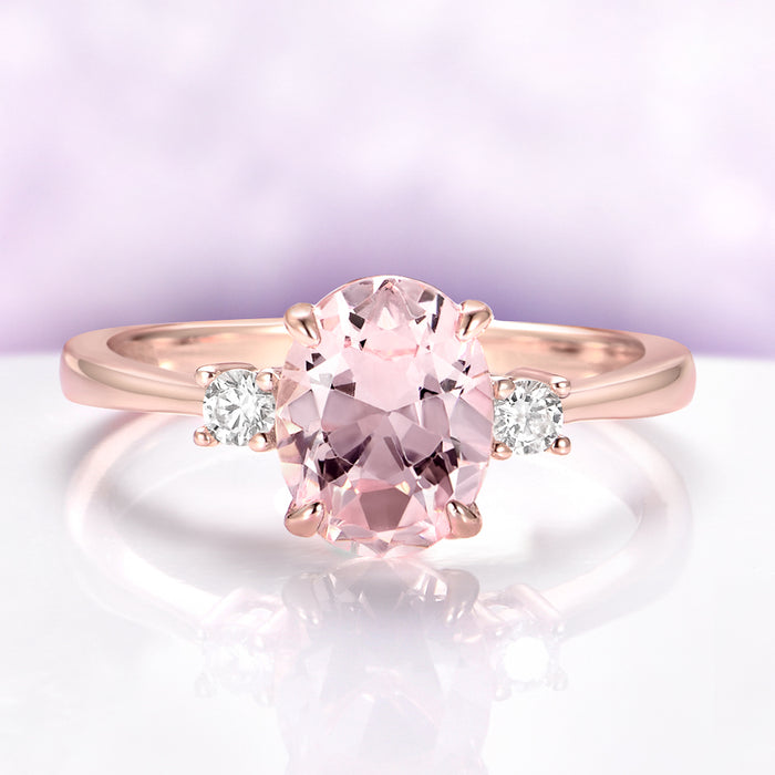 Everly Three Stone Oval Morganite Ring in 14K Rose Gold Vermeil by Aquamarise, featuring a 2 carat oval morganite center flanked by two simulated diamond accents in a classic setting.