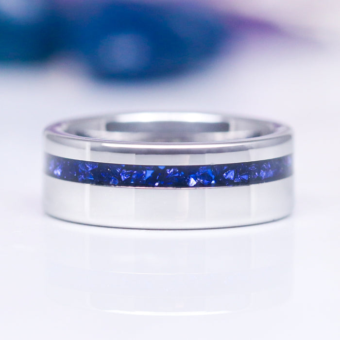 An 8MM tungsten carbide ring with a polished dome design and an offset crushed blue sapphire inlay, displaying a sleek and modern appearance.
