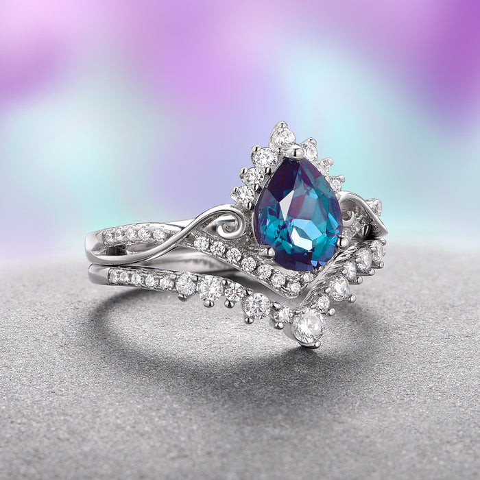 Faye Alexandrite Ring Set- 14K White Gold (Two Piece) by Aquamarise Gold, featuring a pear-shaped alexandrite center stone surrounded by intricate diamond accents on elegantly intertwined white gold bands, from the Nature-Inspired Engagement Rings and June Birthstone Jewelry collections.