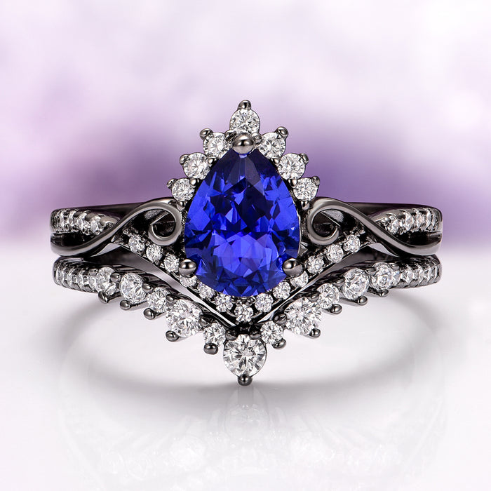 Faye Galaxy Orion Nebula™ & Sapphire Couples Ring Set featuring a striking pear-shaped deep blue sapphire centerpiece framed by sparkling diamonds on a black-finished band with elegant swirling details, crafted by Aquamarise.