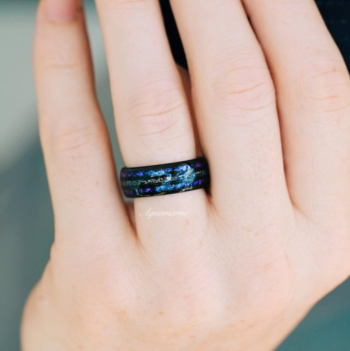 Faye Galaxy Orion Nebula™ & Sapphire Couples Ring Set featuring a black finish band inlaid with vibrant blue and purple sapphire flakes, styled on a hand, part of Aquamarise’s Matching Couples' Rings and Orion Nebula Rings® collections.