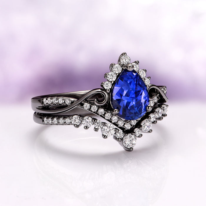 Faye Galaxy Orion Nebula™ & Sapphire Couples Ring Set by Aquamarise featuring a pear-shaped blue sapphire centerpiece surrounded by sparkling diamonds on an elegant black-finished band, part of Matching Couples' Rings and September Birthstone Jewelry collections.