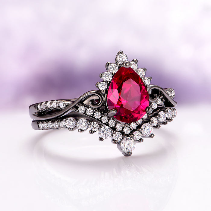Faye Ruby Engagement Ring Set in Black Ruthenium features a pear-shaped ruby center surrounded by sparkling simulated diamonds on a black ruthenium sterling silver band by Aquamarise, inspired by July Birthstone Jewelry and Lovers of the Dark™ collections.