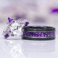 Feyra Amethyst & Simulated Diamond Couples Ring Set featuring a delicate silver ring with a pear-shaped simulated diamond and amethyst accents, paired with a black band inlaid with vibrant crushed amethyst stones, designed by Aquamarise.