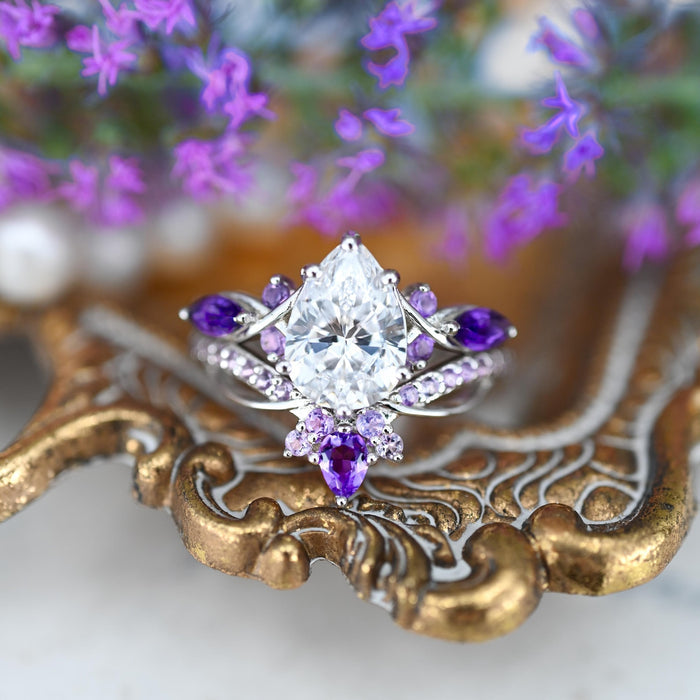 Feyra Amethyst & Simulated Diamond Couples Ring Set by Aquamarise showcasing a pear-shaped simulated diamond surrounded by marquise and round amethyst stones in an intricate silver design, featured in Matching Couples' Rings and Amethyst Jewelry collections.