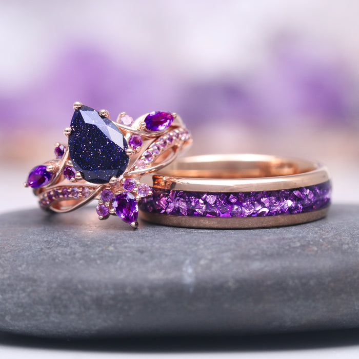 Feyra Starry Night & Amethyst Couples Ring Set featuring a pear-shaped deep blue starry night gemstone with intricate rose gold floral accents and a matching band inlaid with crushed amethyst stones, crafted by Aquamarise.