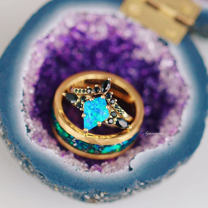 Fire Opal, Meteorite & Starry Night Wedding Band- 8MM Gold Tungsten displayed inside a blue and purple geode ring box, featuring a vibrant faceted blue and green fire opal centerpiece with black stones set in a hammered gold band by Aquamarise.