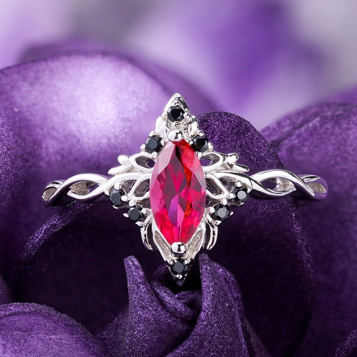 Fire Queen marquise lab-grown ruby ring in sterling silver on purple petals, black onyx accents on the twisted band