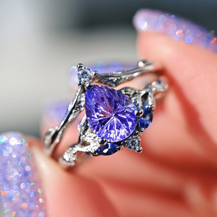 Fireworks Cut Lab-Grown Lavender Sapphire Engagement Ring Set in 14K White Gold featuring a pear-shaped star-cut lavender sapphire surrounded by intricate vine-inspired white gold detailing and small accent stones, crafted by Aquamarise Gold.