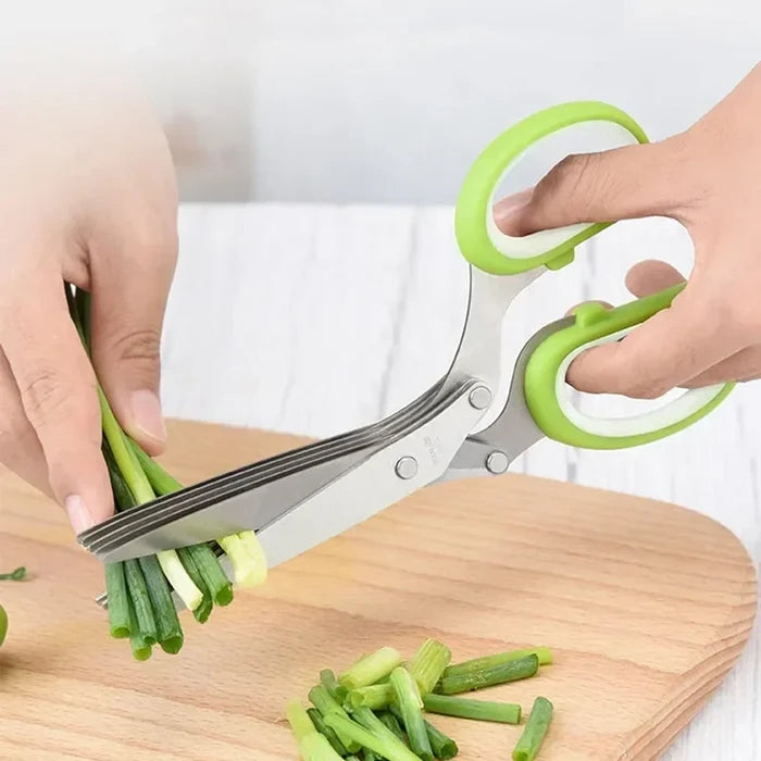Person using five blade herb scissors to chop fresh green onions on a wooden cutting board.