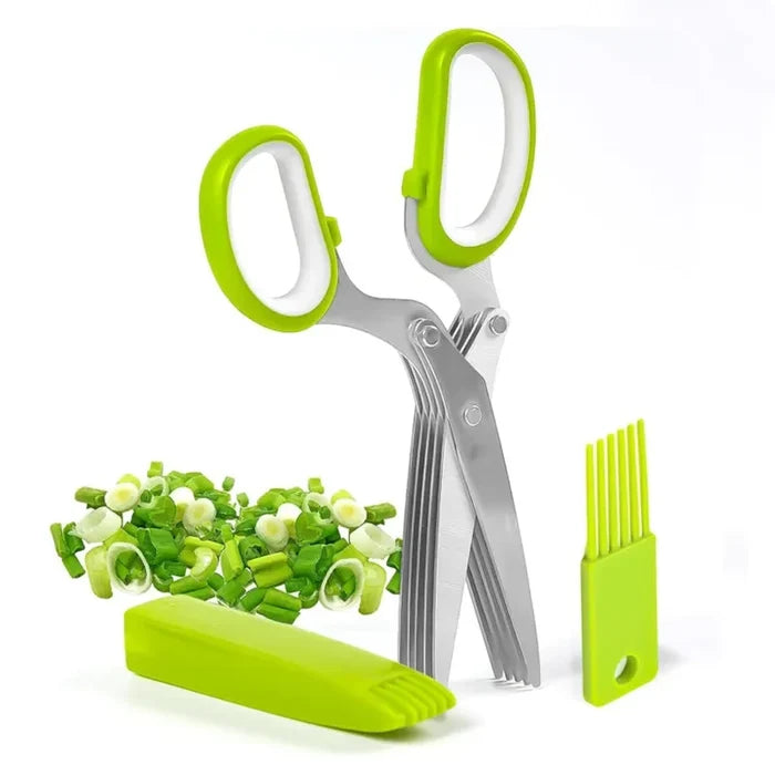 Five blade herb scissors with green handles, standing beside chopped herbs and a cleaning tool.