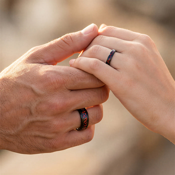 Galaxy Red Fire Opal Hammered Tungsten Couples Ring worn on interlocked hands, showcasing Aquamarise’s matching couples rings with vibrant red opal inlays and hammered black tungsten bands.