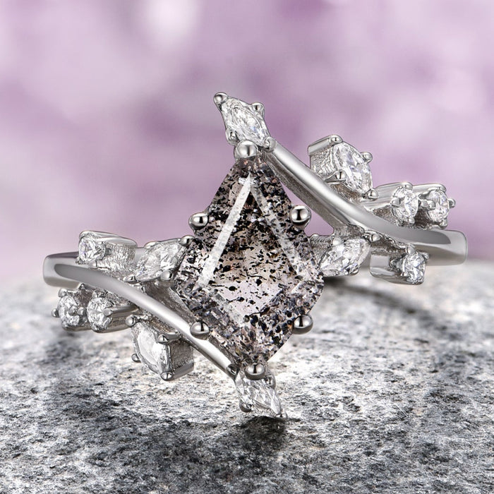 A sterling silver ring featuring a kite-cut Herkimer diamond with salt and pepper inclusions, accompanied by smaller clear stones on the band.