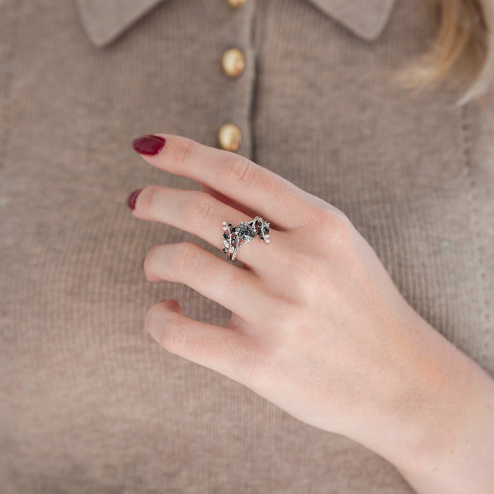 Sterling silver leaf guard wedding band and oval salt and pepper (Herkimer diamond) engagement ring displayed in hand against warm brown backdrop