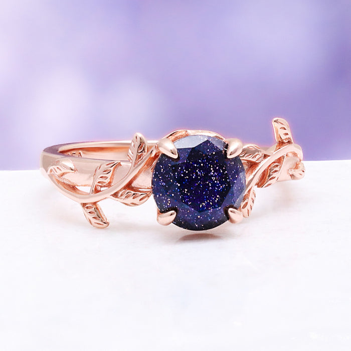 Front view of the leaf and vine shank cradling the sparkling blue galaxy sandstone center stone