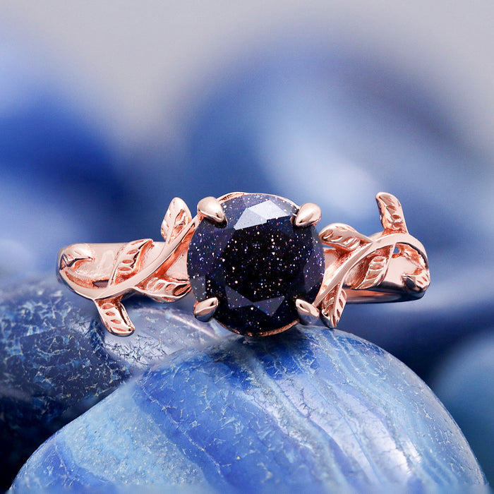 Galaxy sandstone leaf ring resting on blue agate, highlighting the copper flecks in the stone