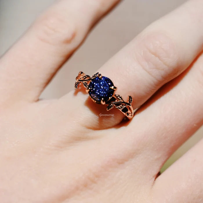 Galaxy Sandstone (Starry Night) Leaf Ring- 14K Rose Gold Vermeil by Aquamarise, featuring a round deep blue sparkling sandstone set in an intricate rose gold vermeil leaf band on finger.
