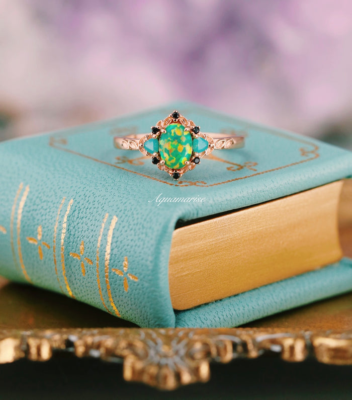 Green Fire Opal Leaf Engagement Ring in 14K Rose Gold Vermeil by Aquamarise with a vibrant green fire opal center, black and opalescent sapphire accents, and intricate leaf design on a delicate band.