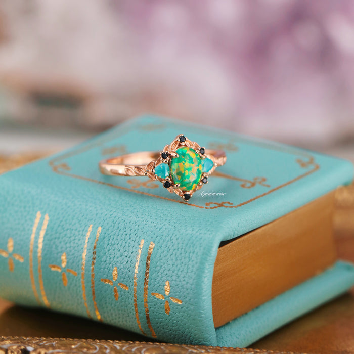Green Fire Opal Leaf Engagement Ring in 14K Rose Gold Vermeil by Aquamarise featuring a vibrant green fire opal center with black and opalescent sapphire accents on a decorative band.