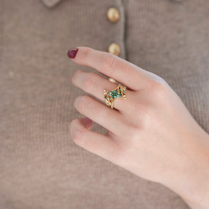 Yellow gold leaf guard wedding band and oval moss agate engagement ring displayed in hand against warm brown backdrop