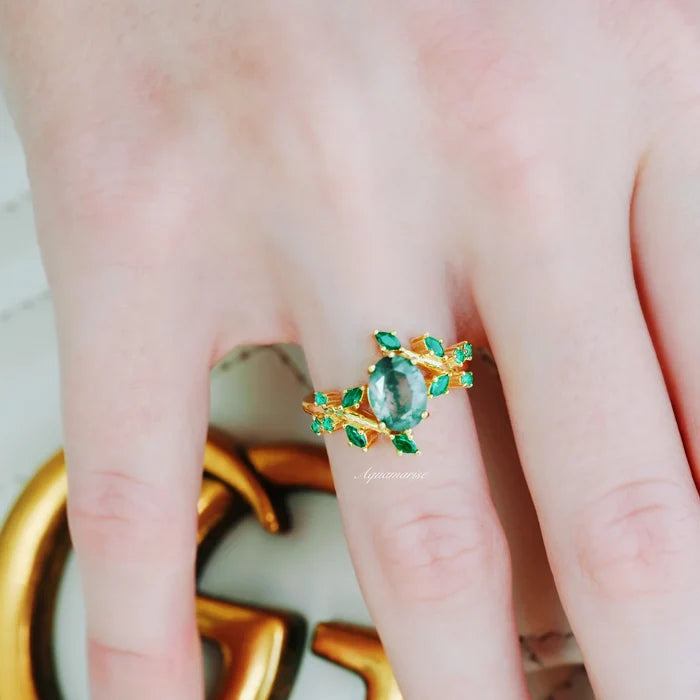 Green Moss Agate & Fire Opal & Gold Leaf Couples Ring Set by Aquamarise featuring a vintage-inspired gold band with delicate leaf motifs, vibrant green moss agate center stone, and fiery opal accents on a hand against a gold accessory backdrop.