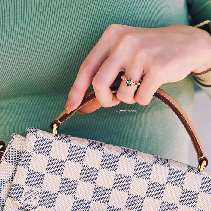 Green Moss Agate Twig Ring in 14K Rose Gold Vermeil by Aquamarise, featuring a pear-shaped moss agate stone with delicate twig-inspired band, styled with a checkered designer handbag.