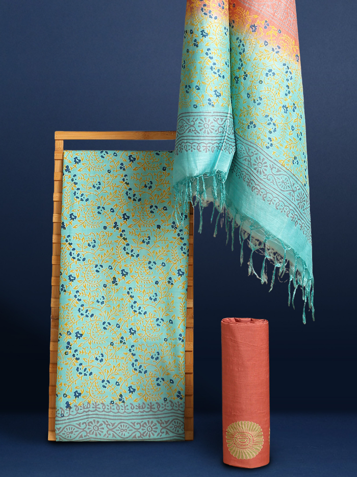 Ombre katan silk unstitched suit set shading from green and turquoise to peach and yellow, with hand block printed leaf vines and a tasselled dupatta