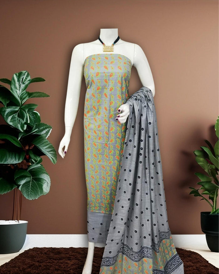Grey Katan silk unstitched suit set with small paisley block print on the top, polka dot print on the remaining pieces in orange, green and black, and a linear band at the dupatta edge