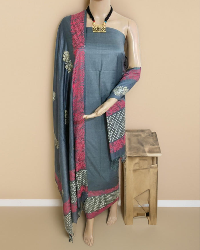 Grey katan silk unstitched suit set with sparse block-printed floral motifs and a wide pink and white border of florals over a geometric grid.