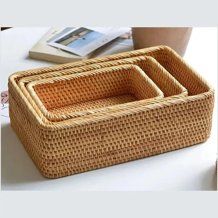 Handwoven rattan storage basket set stacked on a table, showcasing their natural texture and rectangular design.