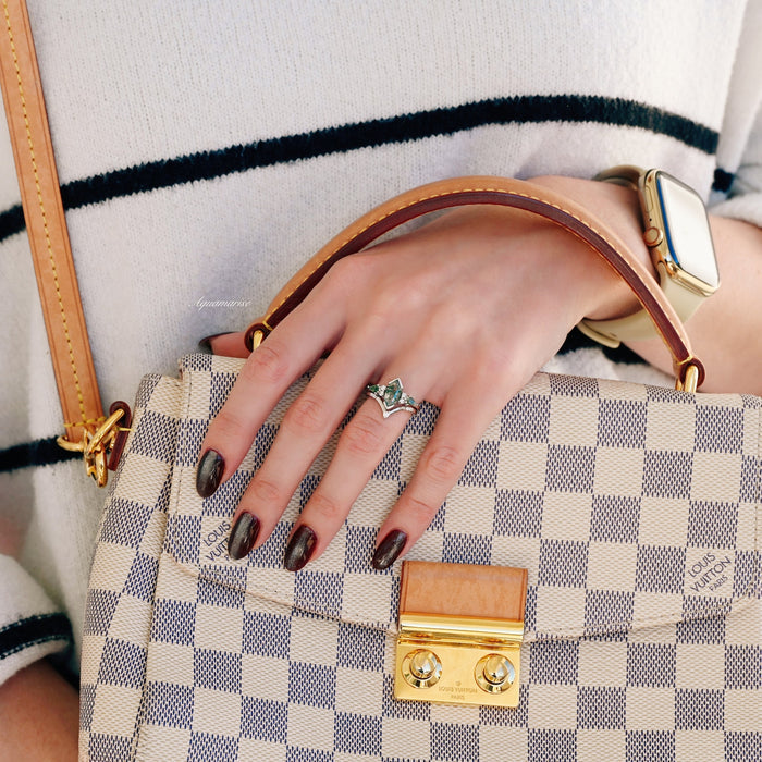 Hand wearing Hexagon Coffin Green Moss Agate Couples Ring Set by Aquamarise, resting on a designer checkered handbag with dark polished nails and a gold smartwatch.