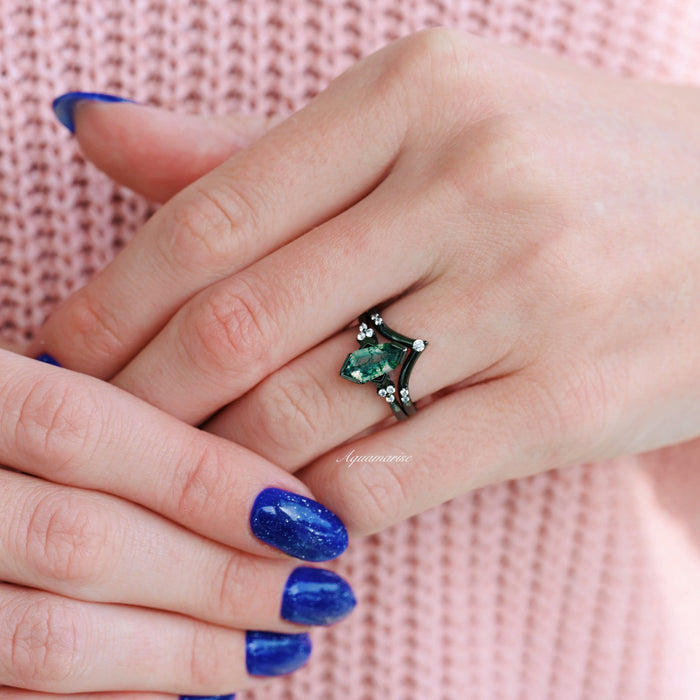 Hexagon Coffin Green Moss Agate Engagement Ring Set in Black Ruthenium by Aquamarise, worn on finger with blue nail polish and soft pink knitted background.