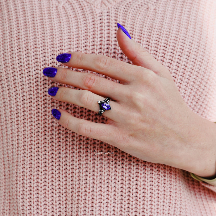 Hexagon Coffin Tanzanite Engagement Ring Set in Black Ruthenium on a hand with deep purple nails, styled with a soft pink knit sweater by Aquamarise.
