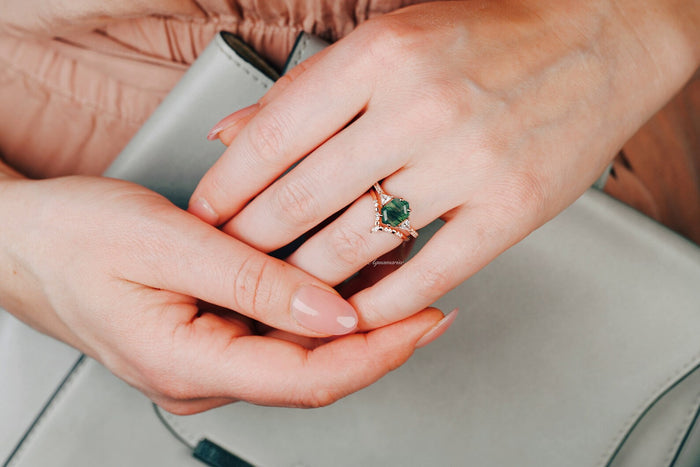 Hexagon Cut Green Moss Agate Engagement Ring Set in 14K Solid Rose Gold by Aquamarise Gold, worn on a hand with manicured nails resting on a soft gray purse.
