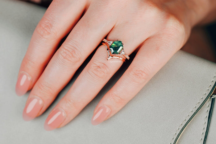 Hexagon Cut Green Moss Agate Engagement Ring Set in 14K Solid Rose Gold by Aquamarise Gold, featuring a striking green moss agate with delicate rose gold bands on a hand resting on a gray purse.