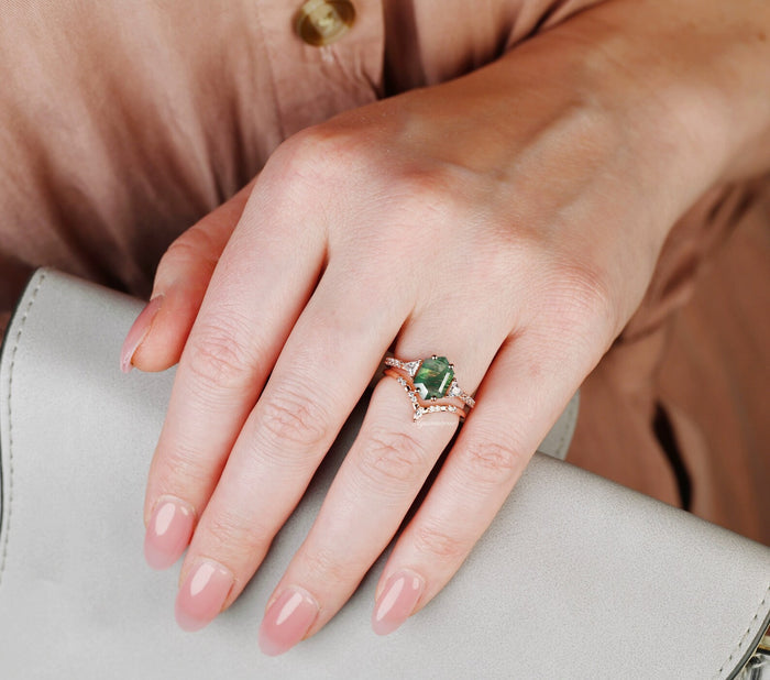 Hexagon Cut Green Moss Agate Engagement Ring Set in 14K Solid Rose Gold by Aquamarise Gold, featuring a vintage-inspired green moss agate and delicate rose gold bands on a hand holding a gray purse.
