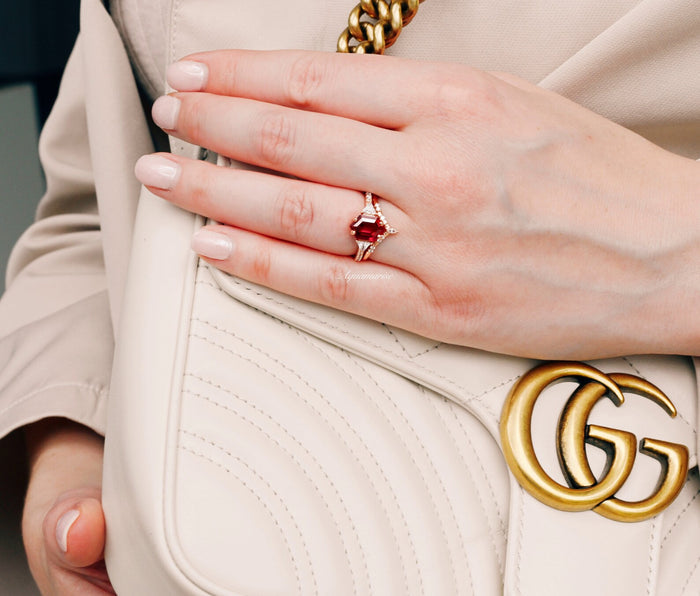 Hexagon Ruby Engagement Ring Set in 14K Solid Rose Gold worn on hand holding a cream leather bag with gold chain, styled with nude polished nails by Aquamarise Gold.
